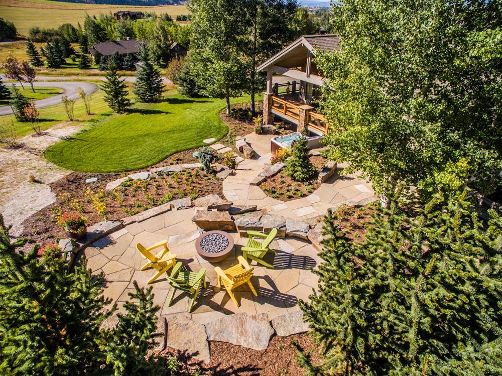 Landscaped backyard patio with fire pit and chairs
