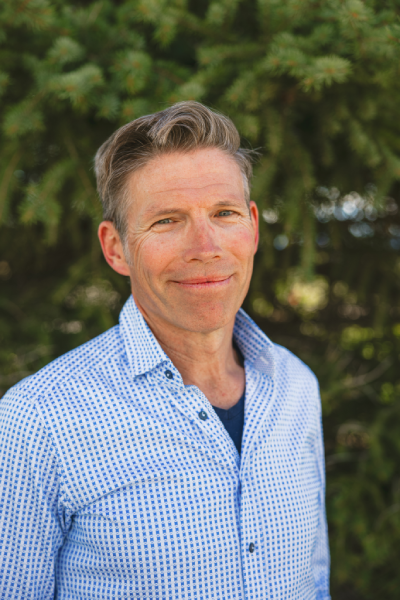 Smiling man in blue patterned shirt outdoors