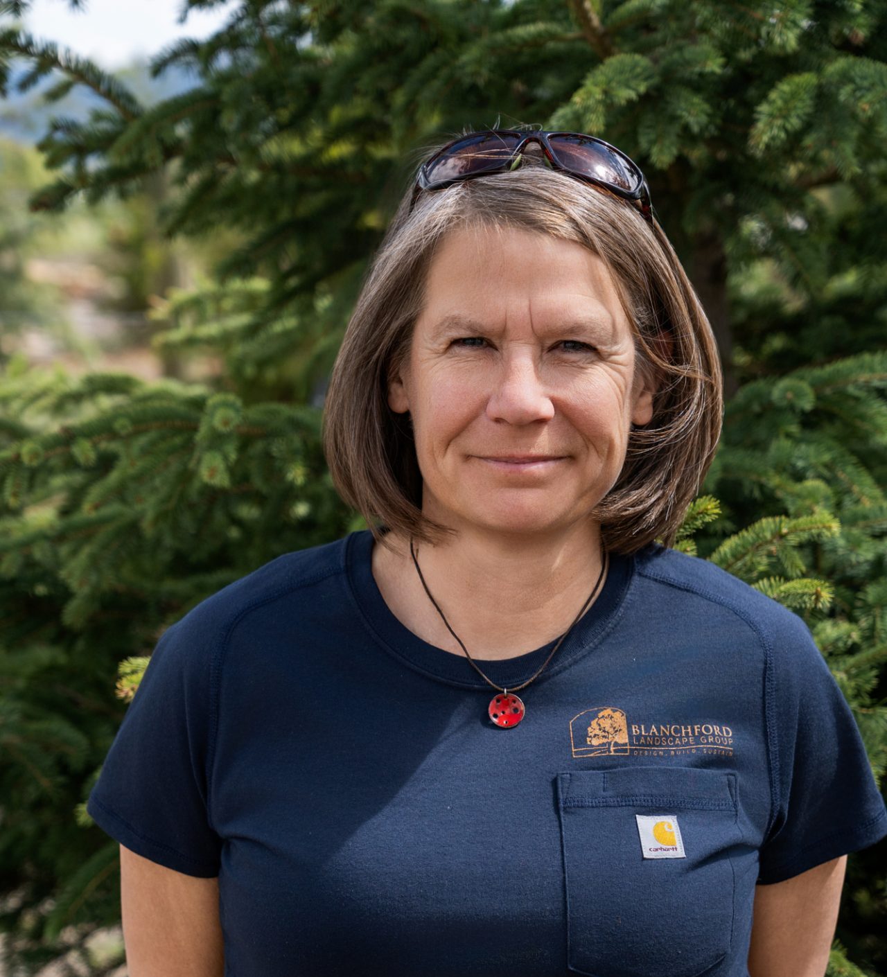 Woman standing before evergreen trees outdoors
