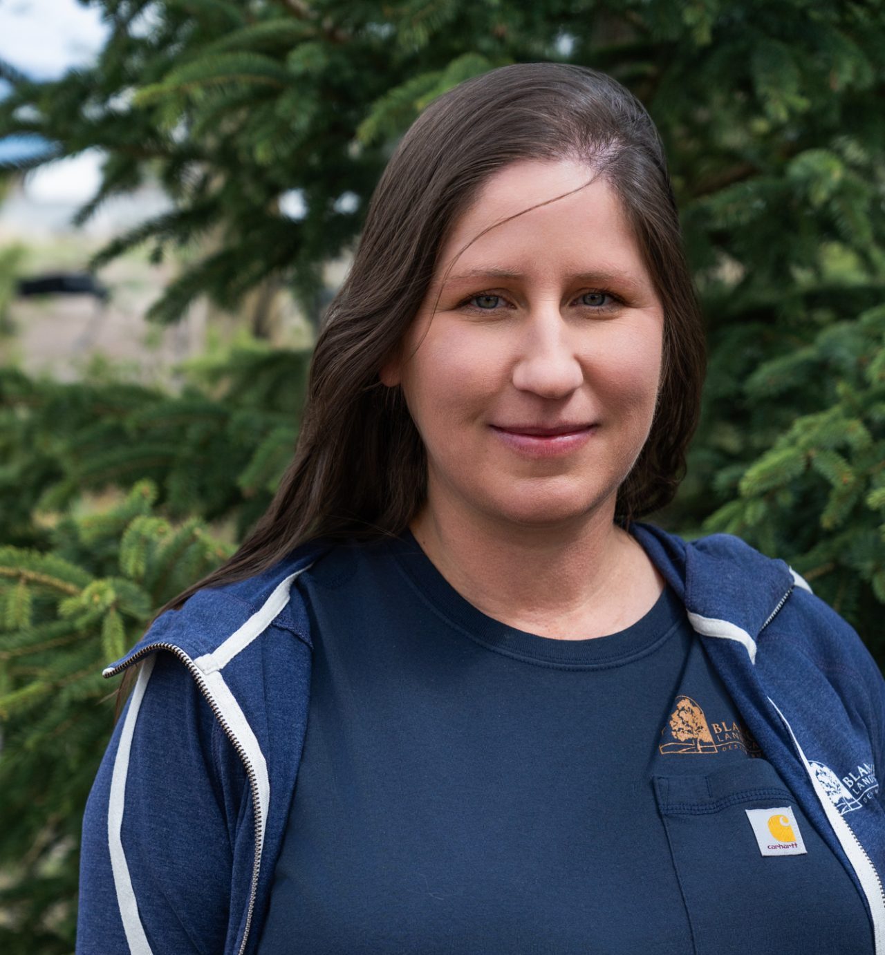 Woman standing outdoors in front of evergreen trees
