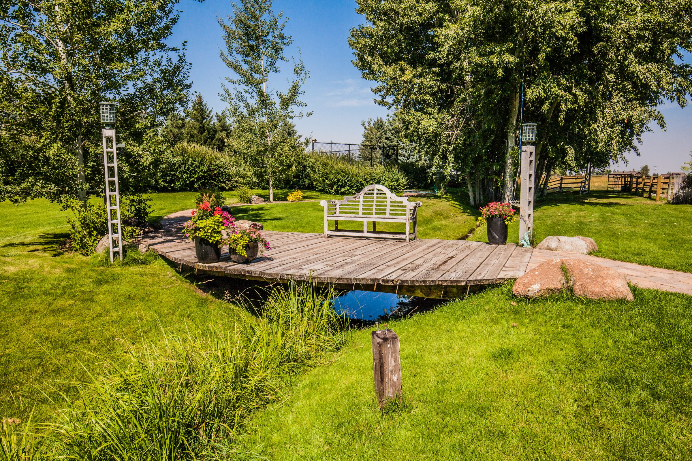 Wooden garden deck with bench over small pond