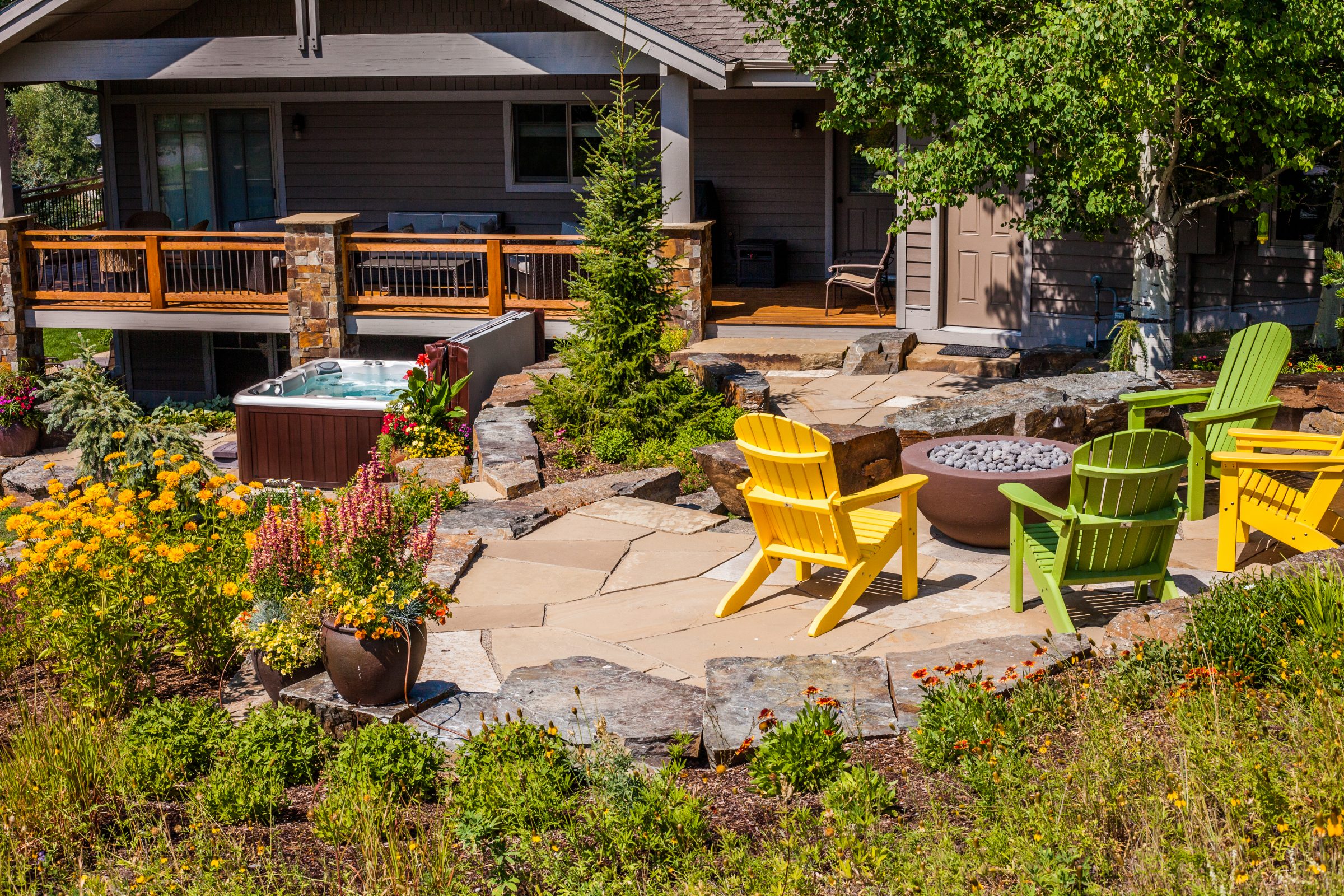 Landscaped backyard patio with fire pit and hot tub