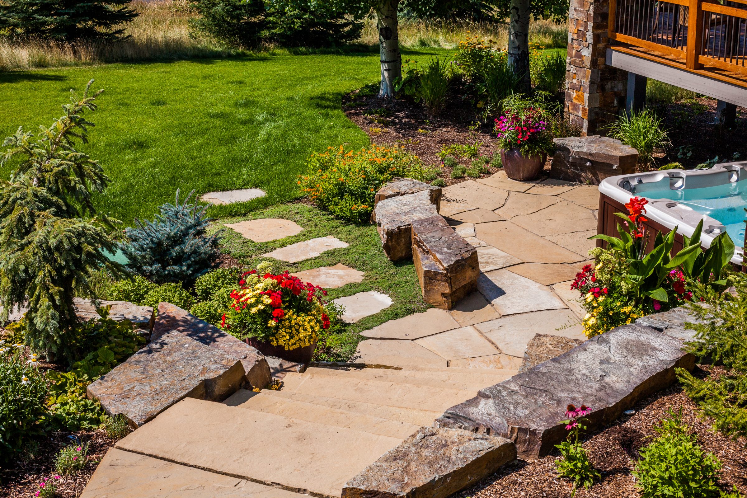 Landscaped backyard patio with hot tub and flowers