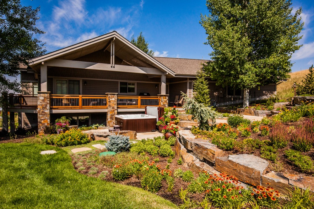 Landscaped backyard with patio, hot tub, and deck
