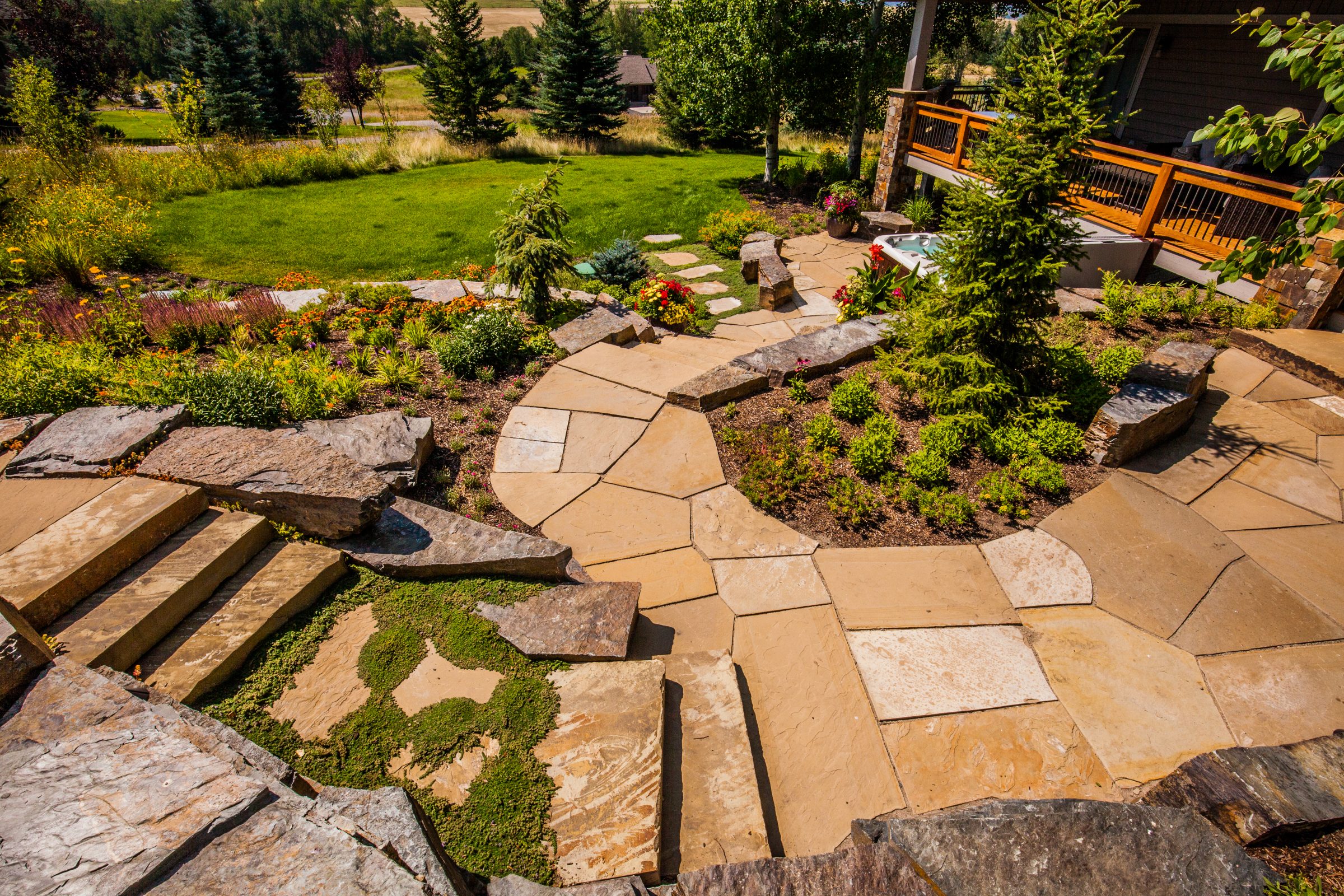 Landscaped backyard with stone patio and garden beds