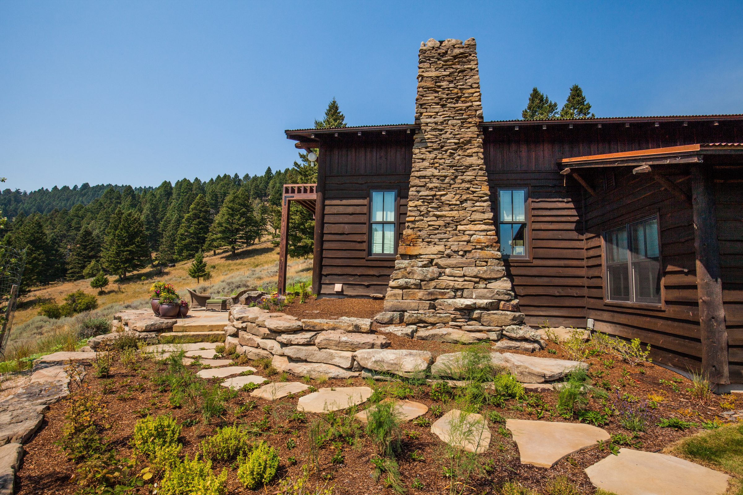 Rustic cabin with stone chimney and forest backdrop