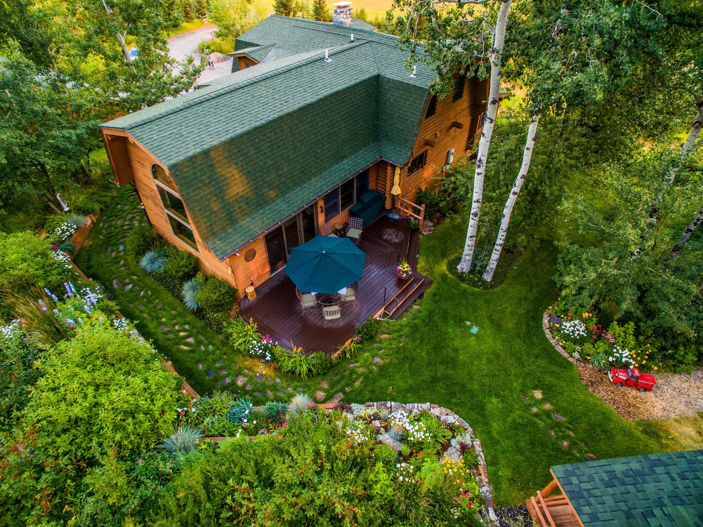 Aerial view of wooden cabin with lush garden