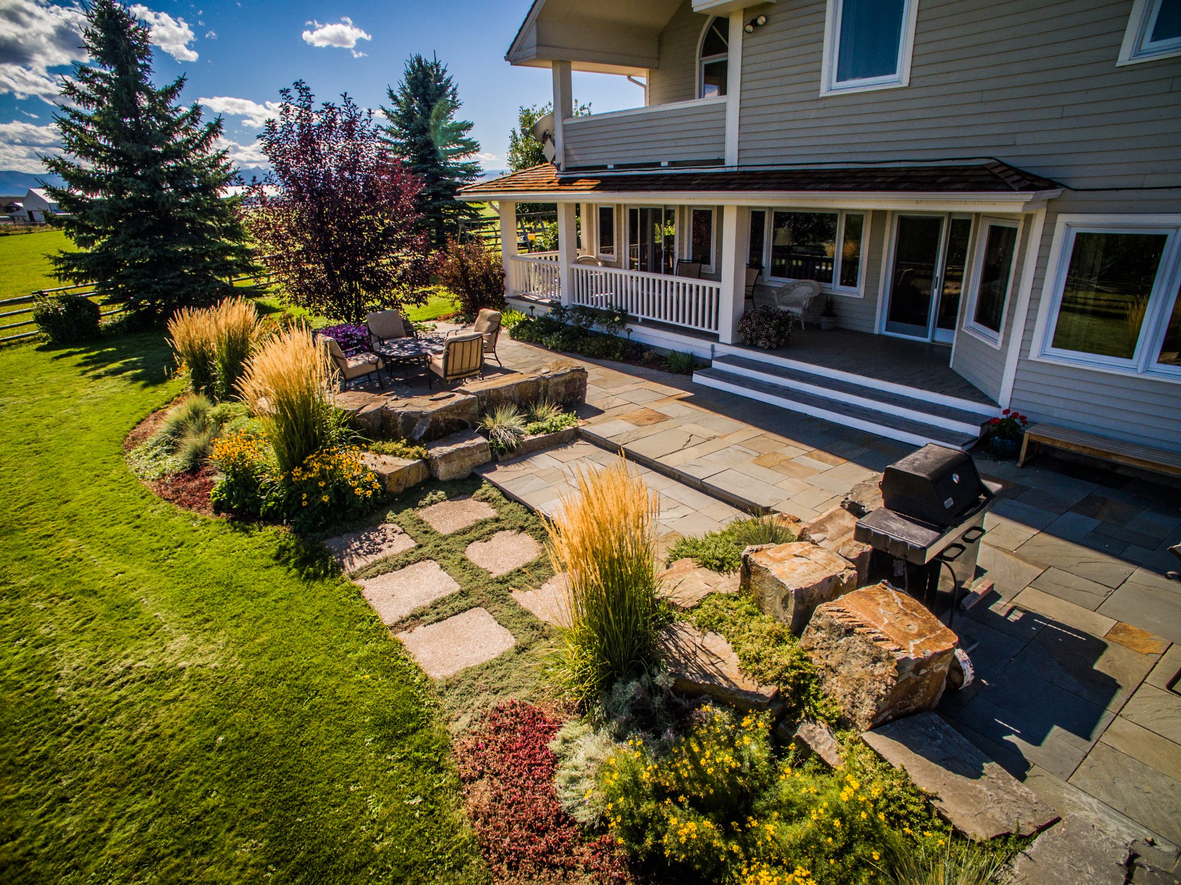 Landscaped backyard patio with seating and grill