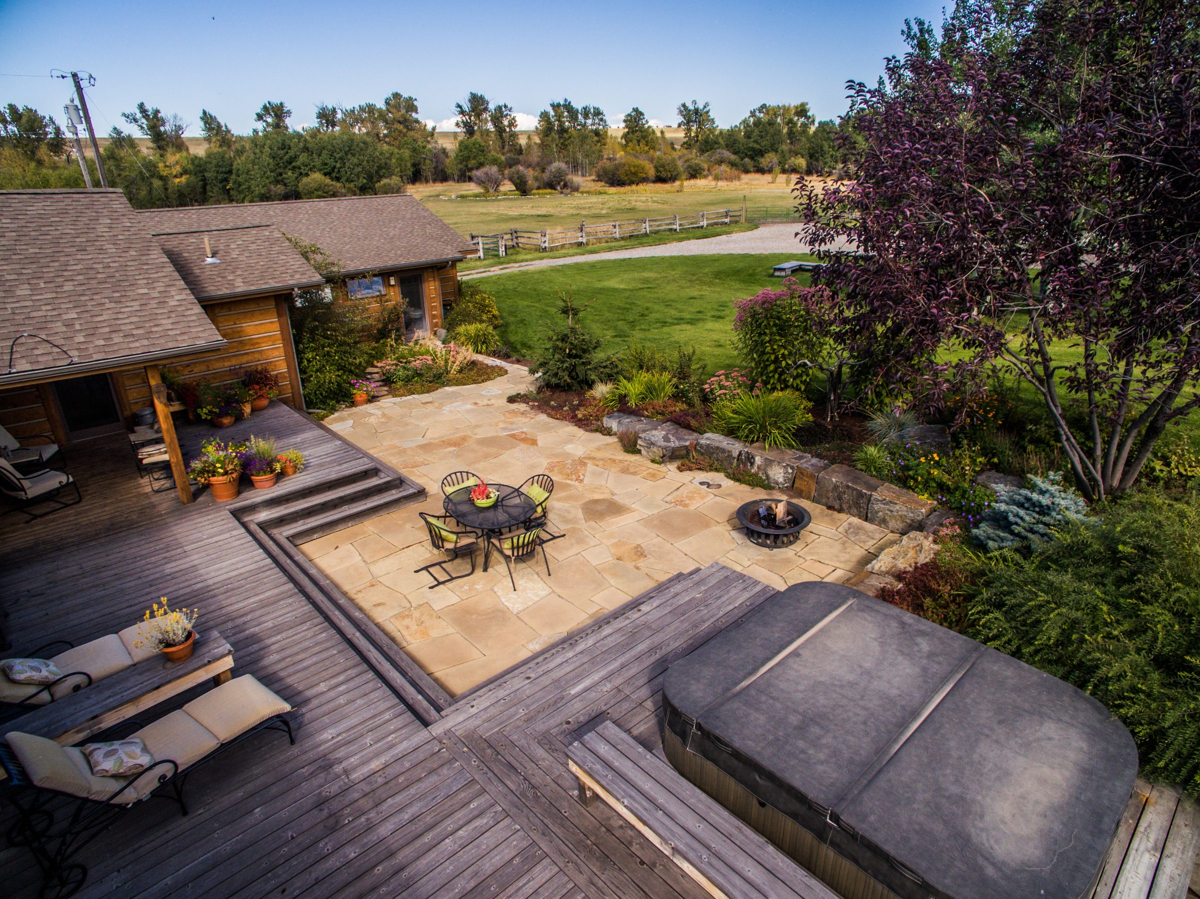 Rustic backyard patio with deck, hot tub, lawn