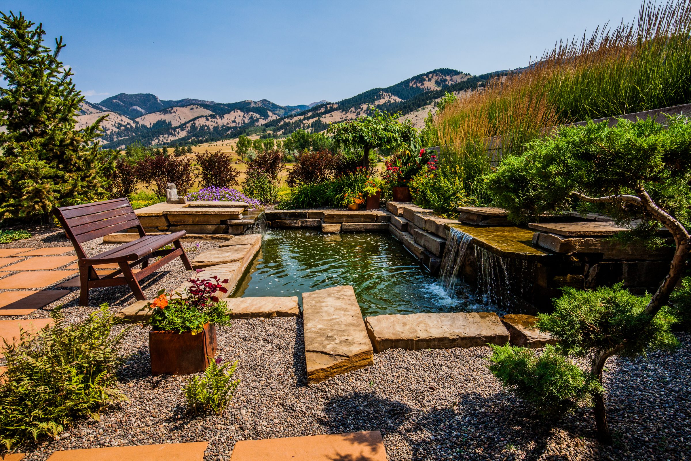 Landscaped backyard pond with waterfall and mountain view