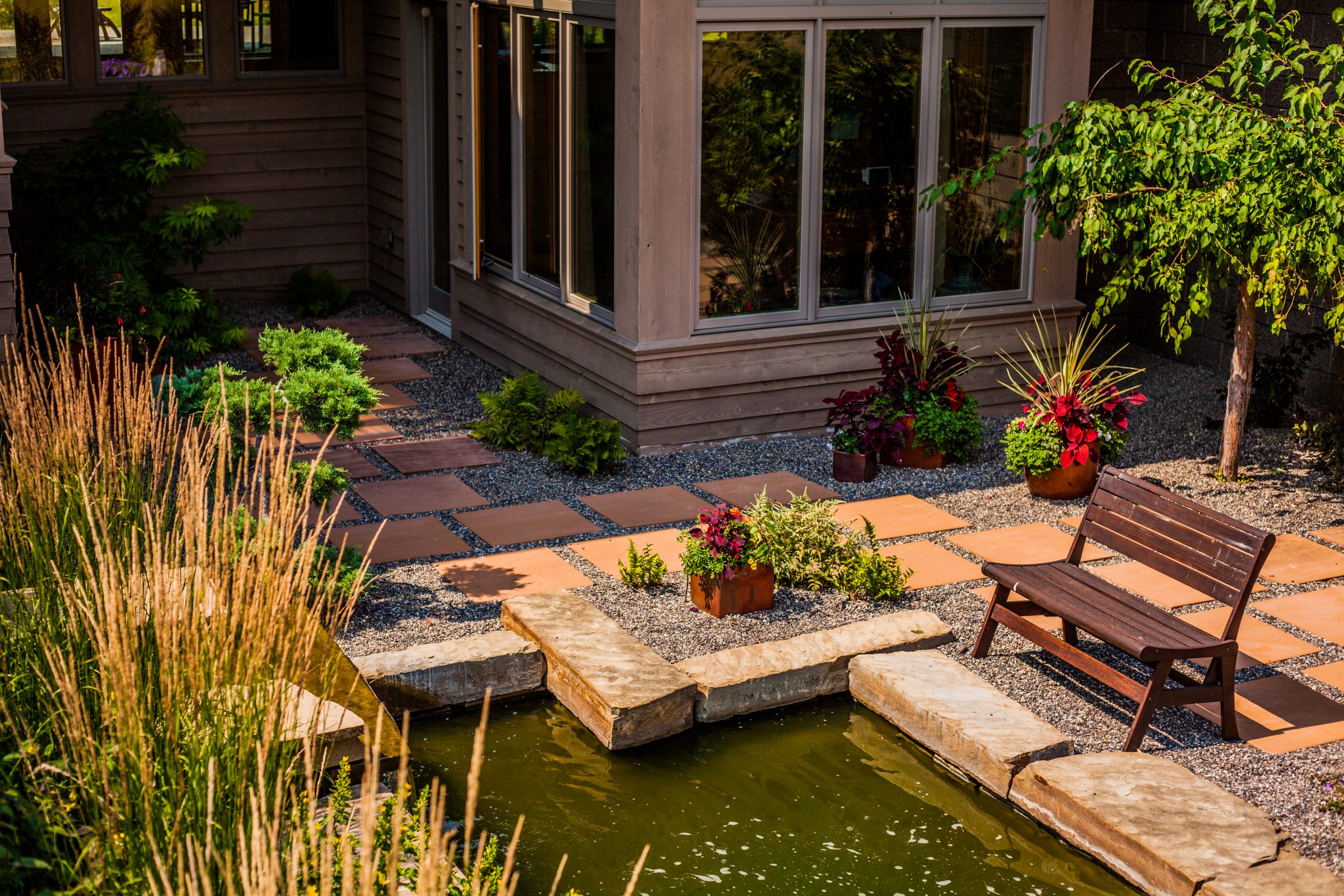 Modern backyard patio with pond and wooden bench