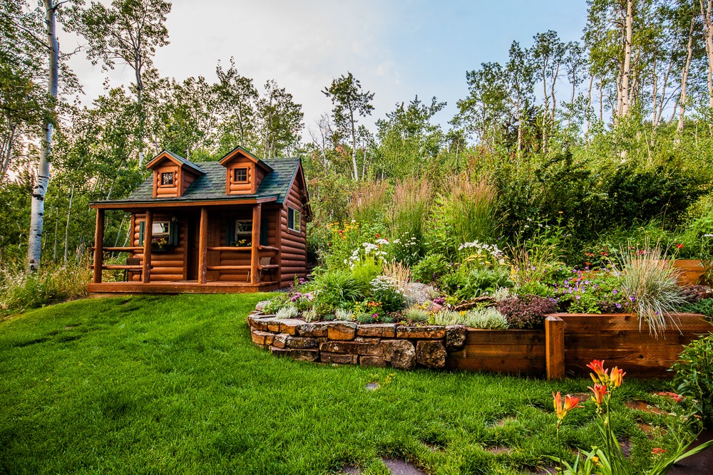 Small log cabin beside lush garden and lawn