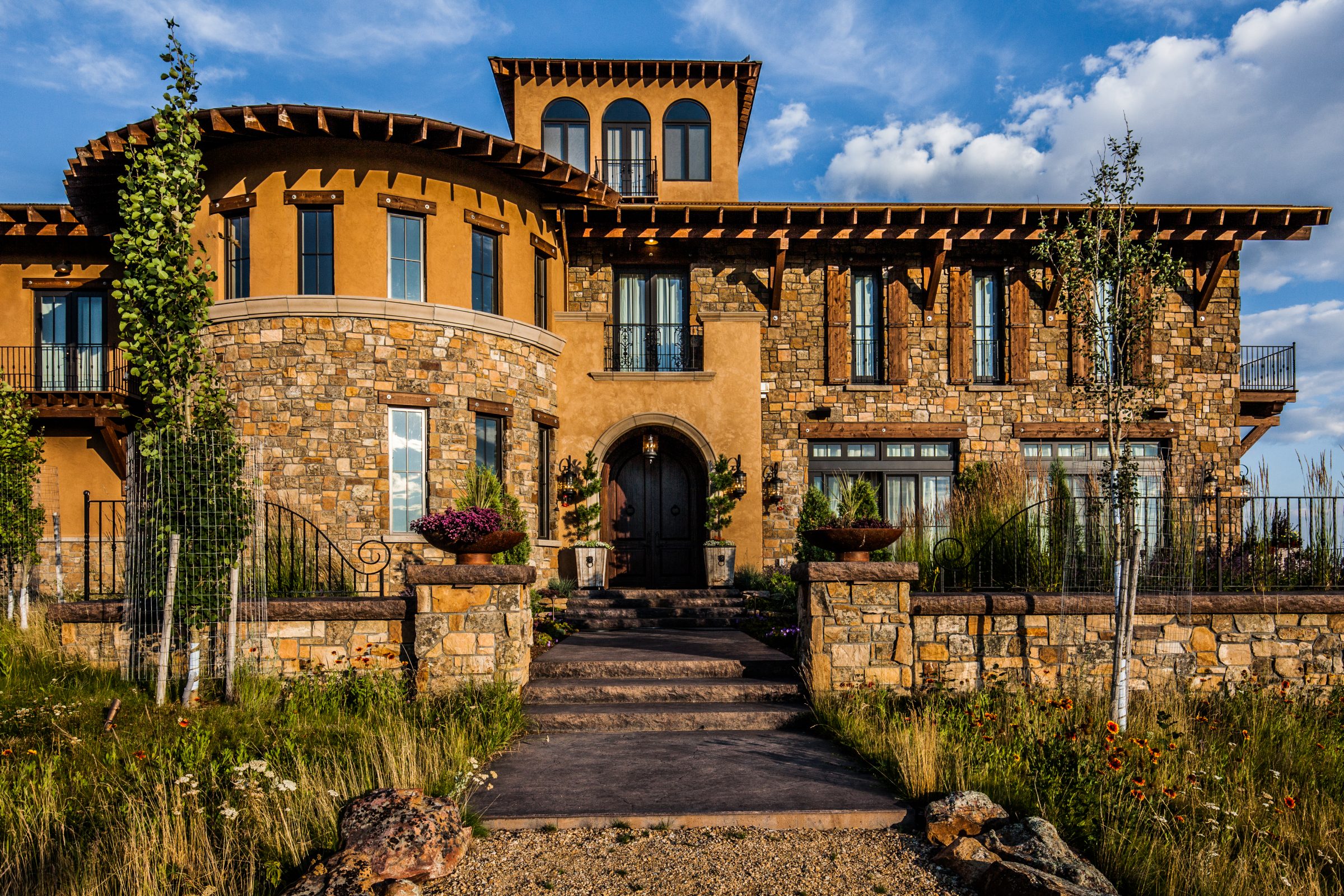 Mediterranean-style luxury home with stone facade and arched entrance