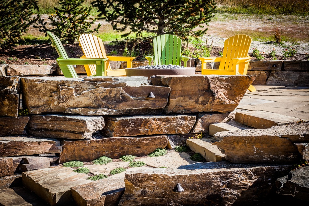 Colorful Adirondack chairs around stone fire pit