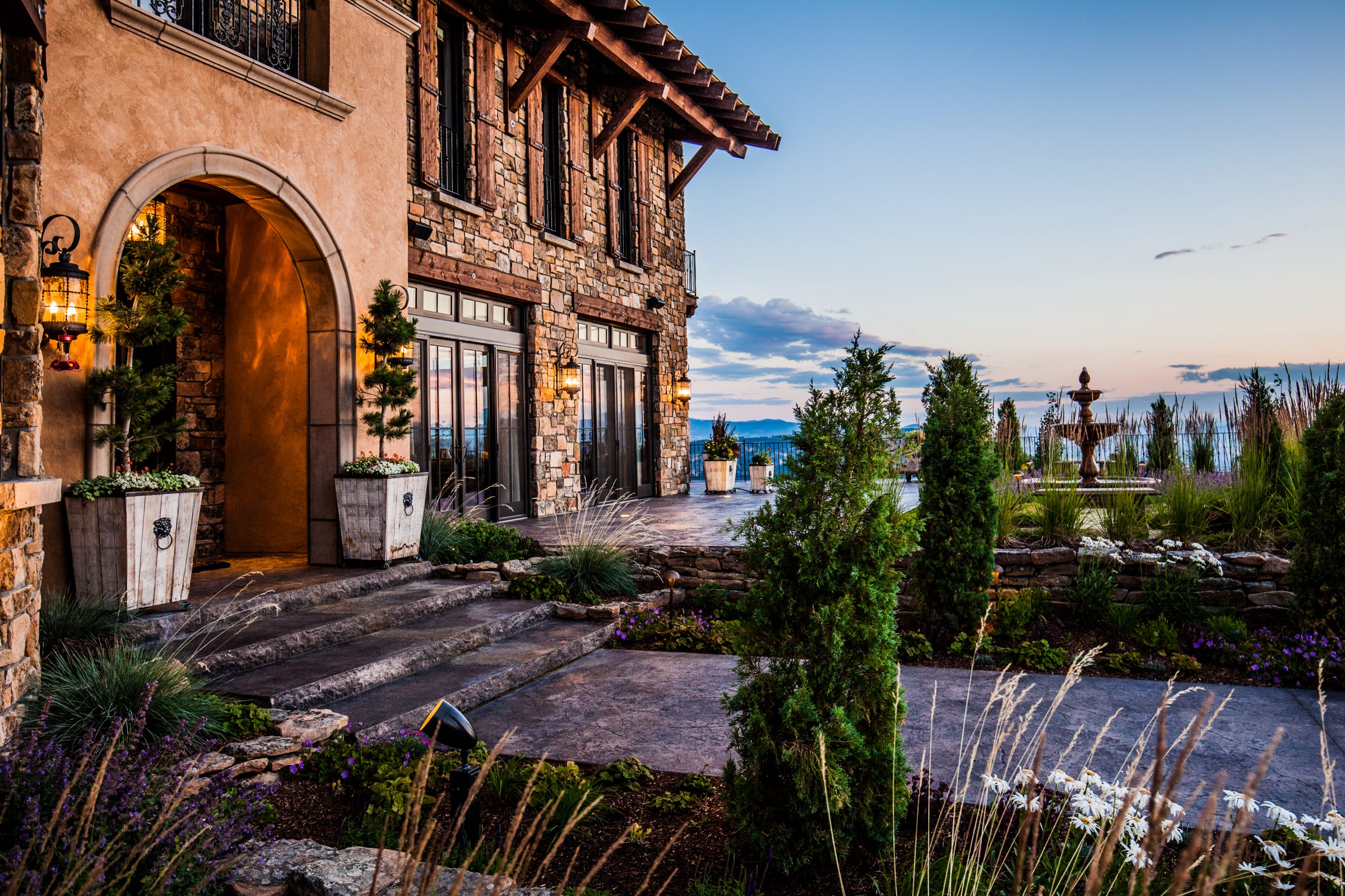 Luxury stone house with landscaped garden at dusk