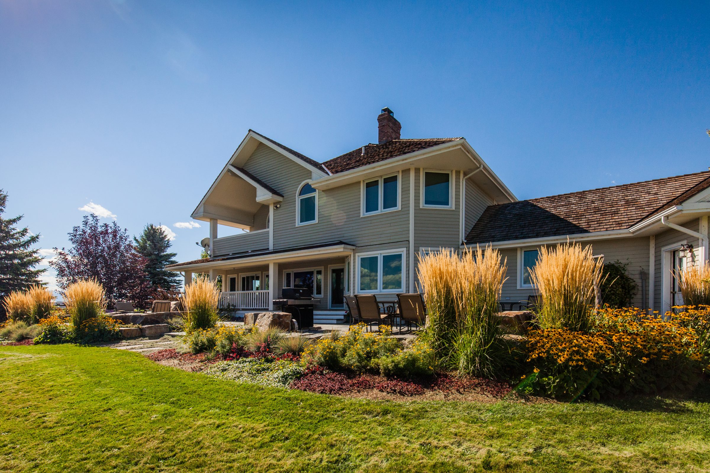 Large suburban home with landscaped backyard and patio