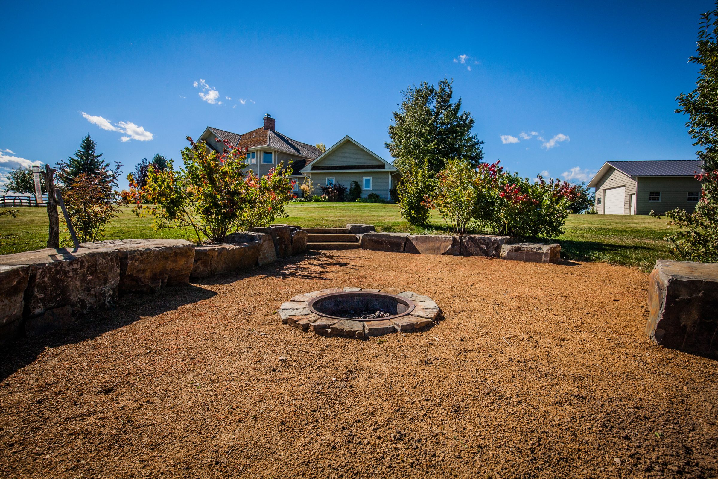 Backyard fire pit with stone seating and house