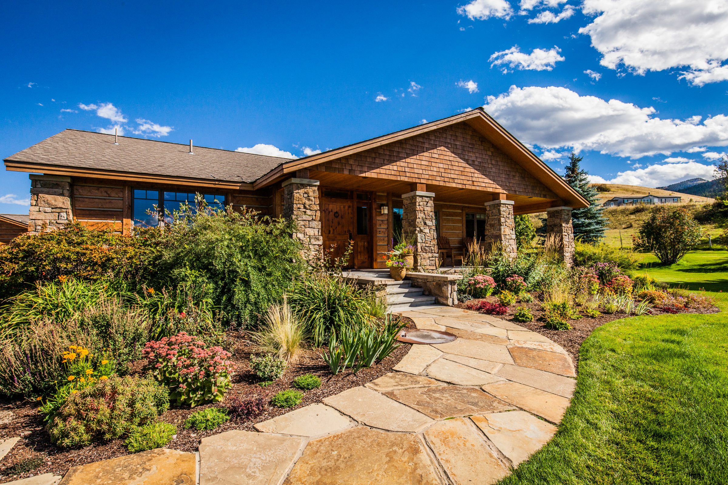 Craftsman home with stone columns and garden