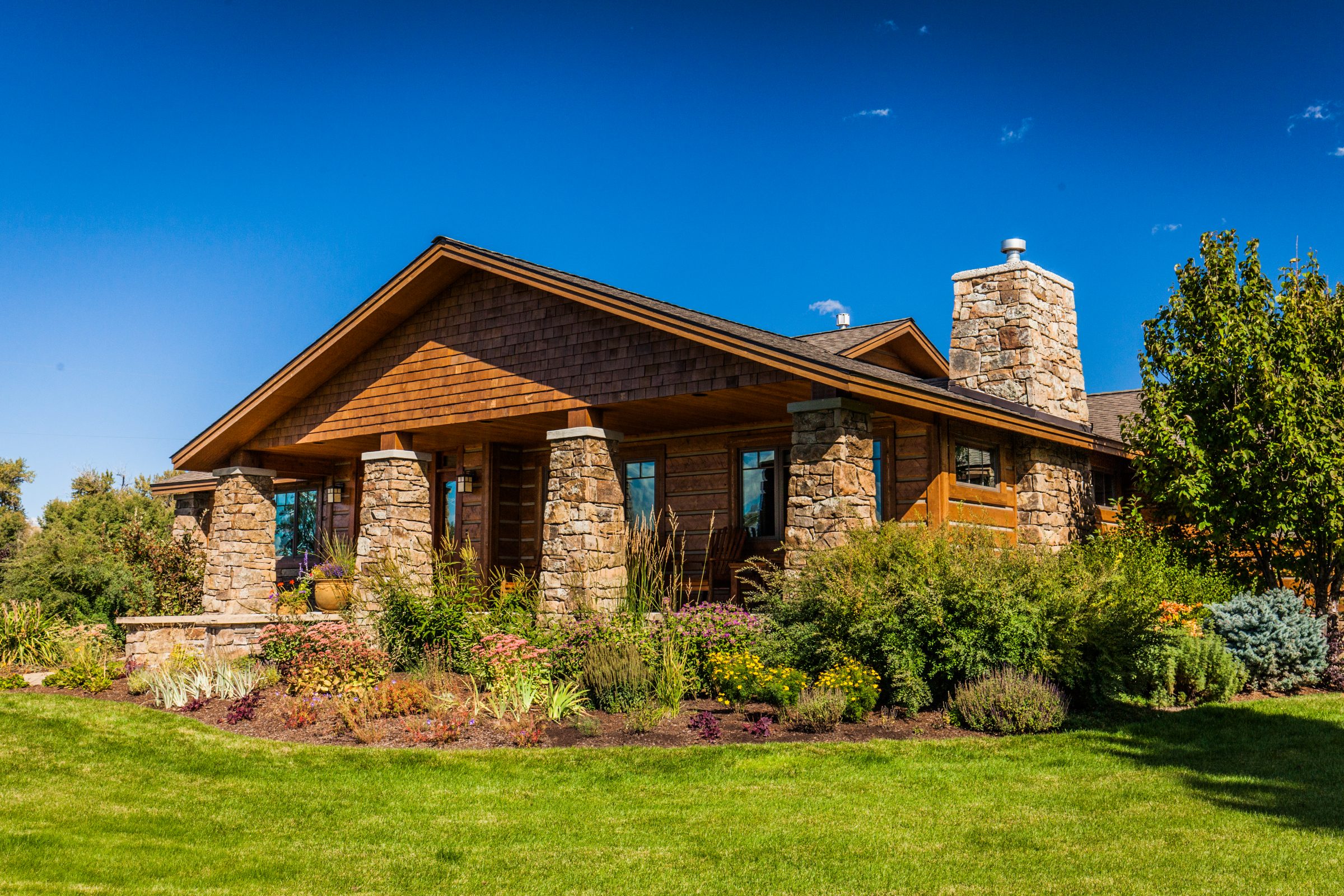 Craftsman-style home with stone columns and garden