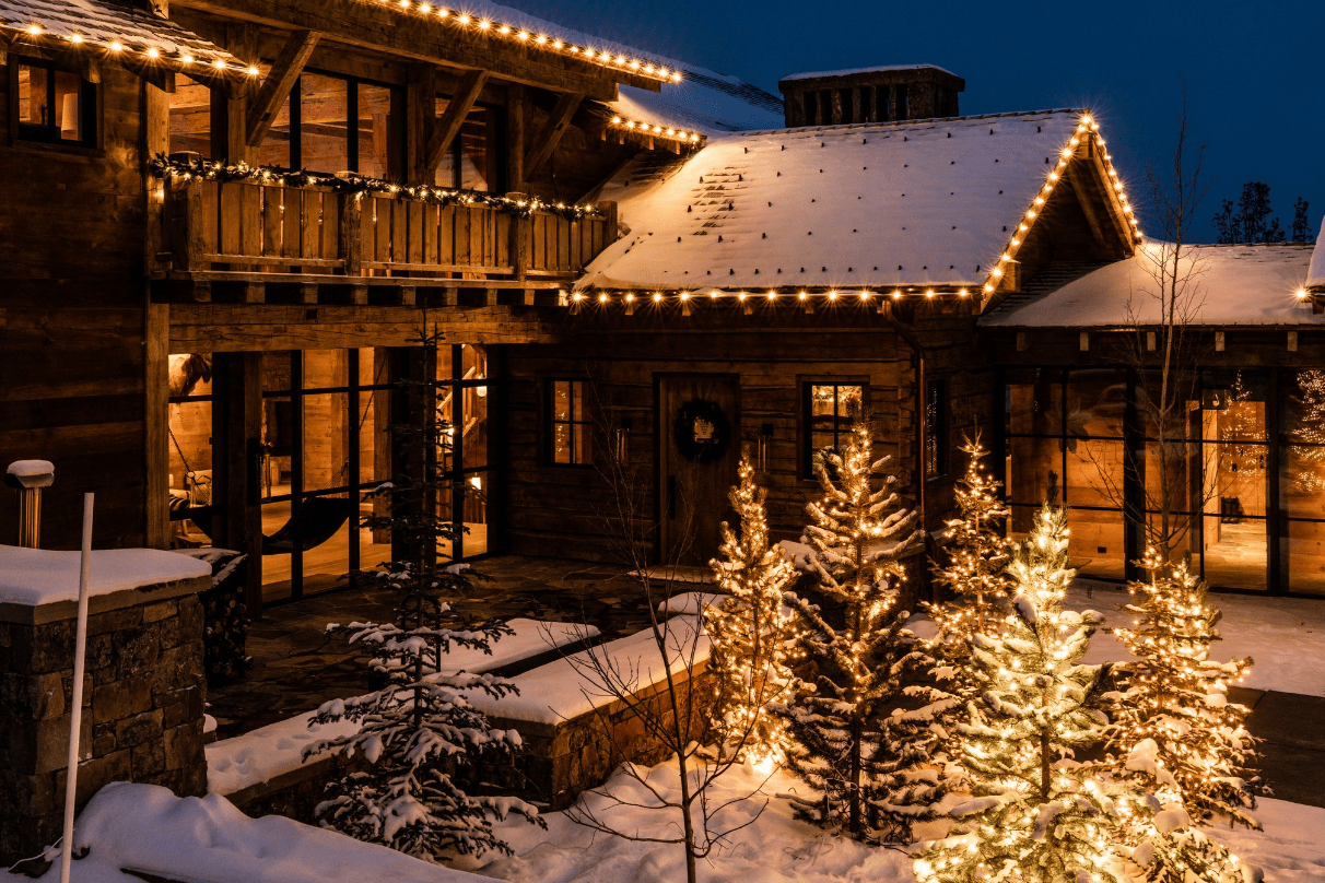 Snowy cabin decorated with warm holiday lights at night