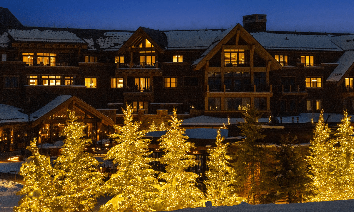 Snowy mountain lodge with illuminated Christmas trees