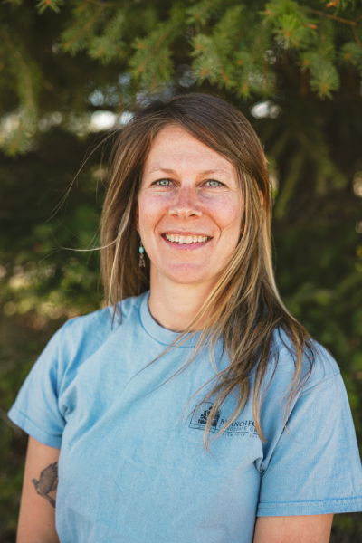 Smiling woman outdoors with trees in background