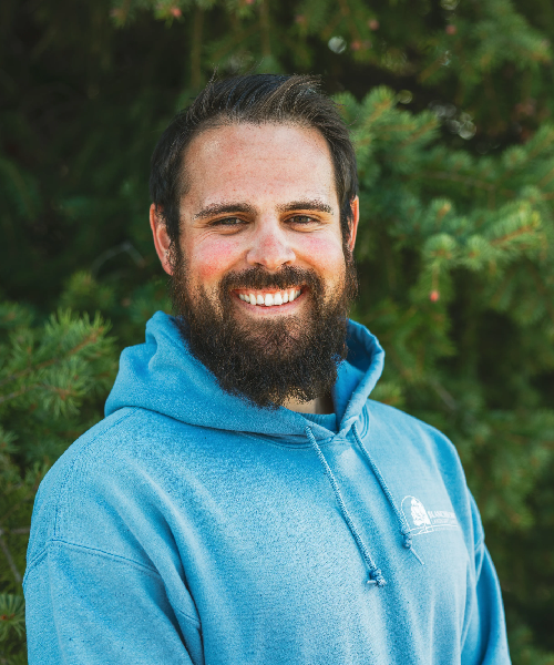 Smiling bearded man in blue hoodie outdoors