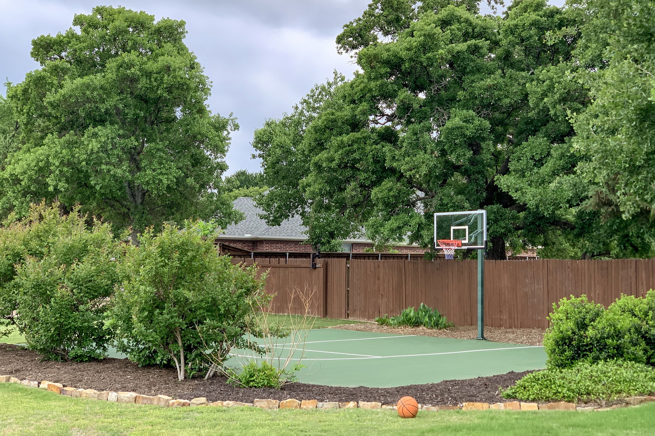 Backyard basketball court with hoop and trees