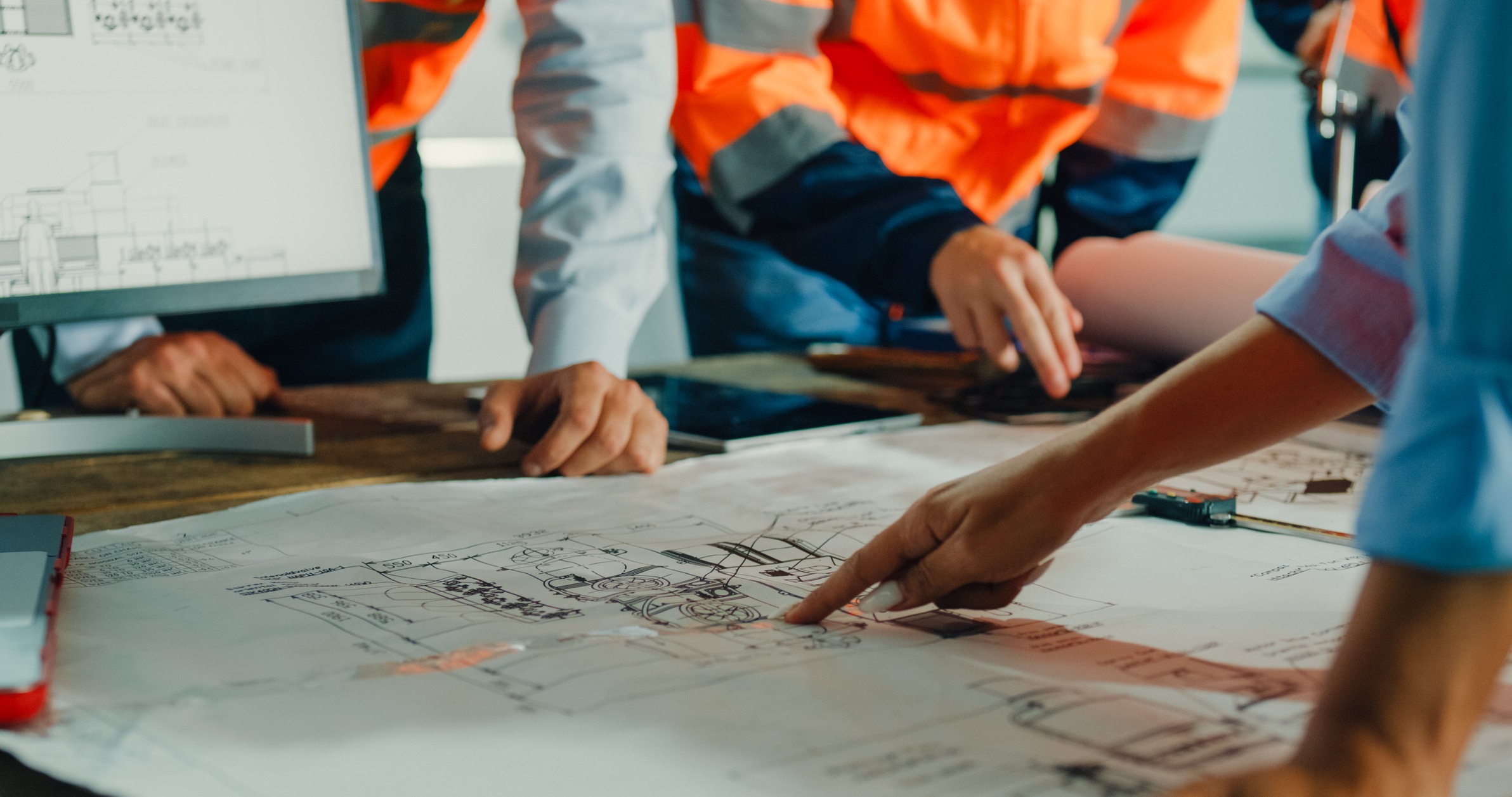 Construction team reviewing blueprints at worksite table