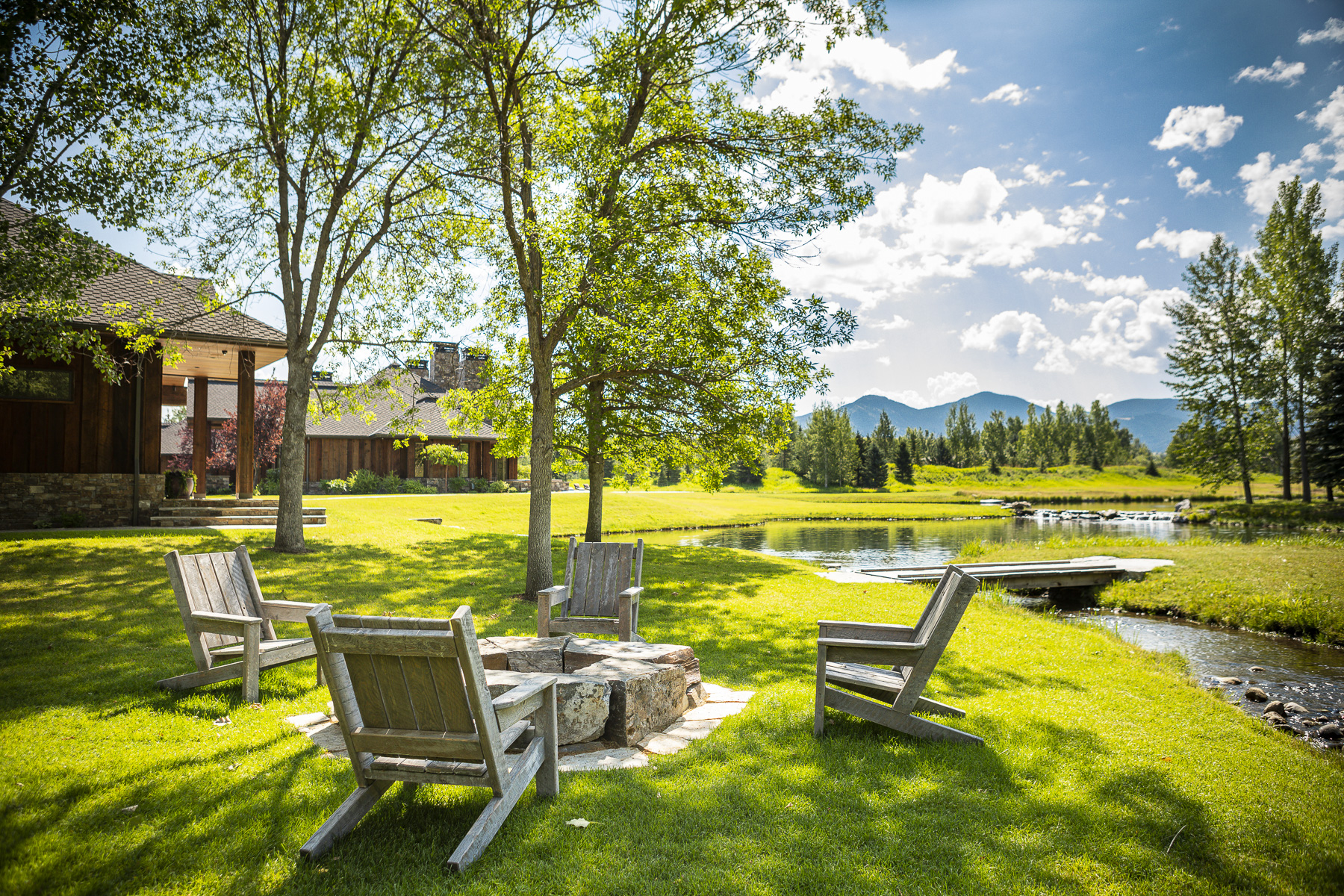 Wooden chairs around fire pit by pond